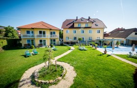 Gartenanlage mit gelben Gebäuden und Liegestühlen bei sonnigem Wetter.