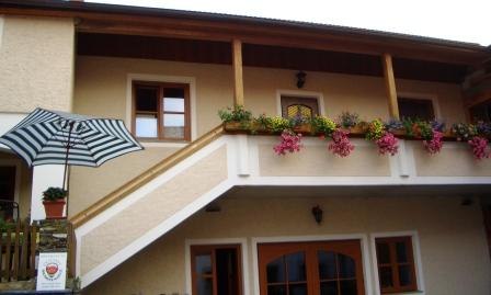 Zweistöckiges Gebäude mit Balkon und Blumen.
