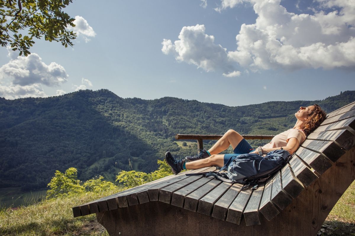 Eine Frau sonnt sich auf einer großen hölzernen Sonnenliege. 