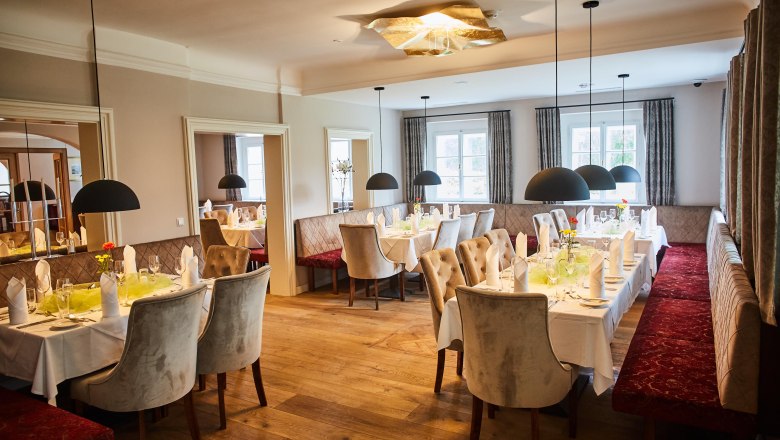 Elegantes Restaurant mit gedeckten Tischen, Polsterbänken und Hängelampen im Schloss Luberegg