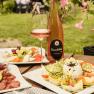 A table set outside with wine, salad and cheese platter at the Strawanzer wine tavern