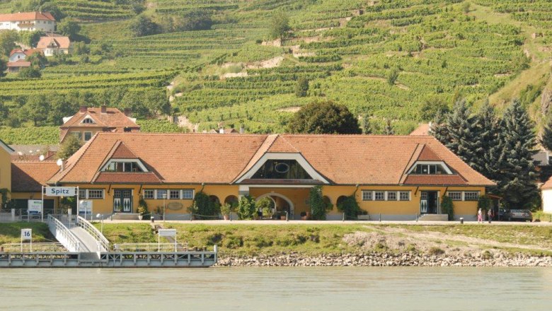Gelbes Geb&auml;ude mit rotem Dach vor Weinbergen in Spitz an der Donau.