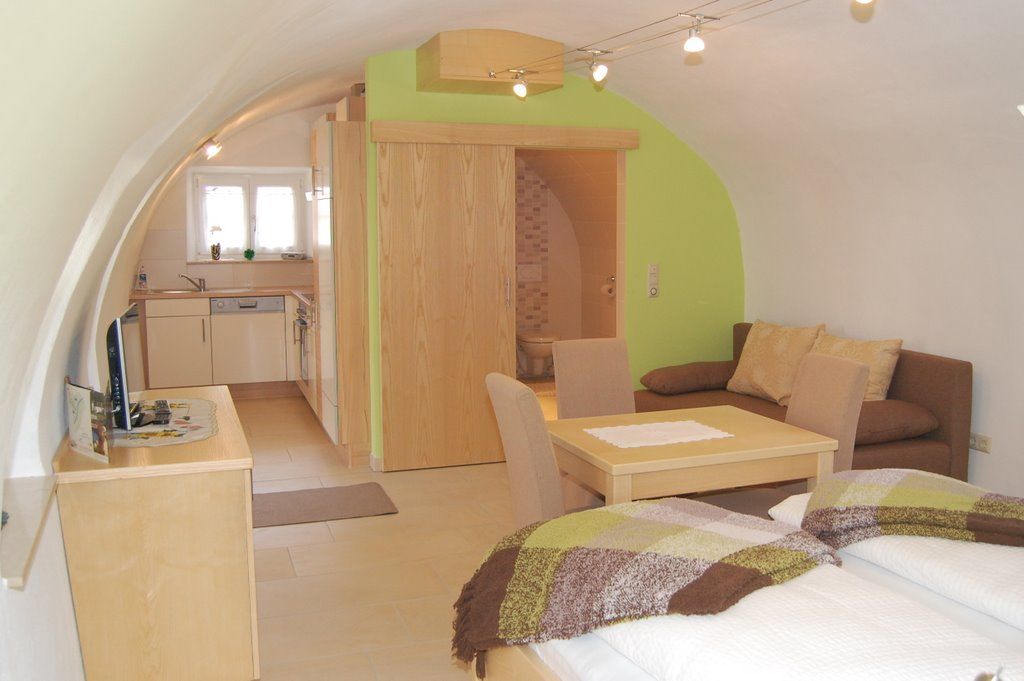 Gemütliches Apartment mit gewölbter Decke, Küche, Esstisch, Sofa und Bett.