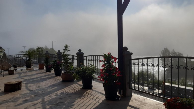 Terrace with plants, railings and fog in the background.