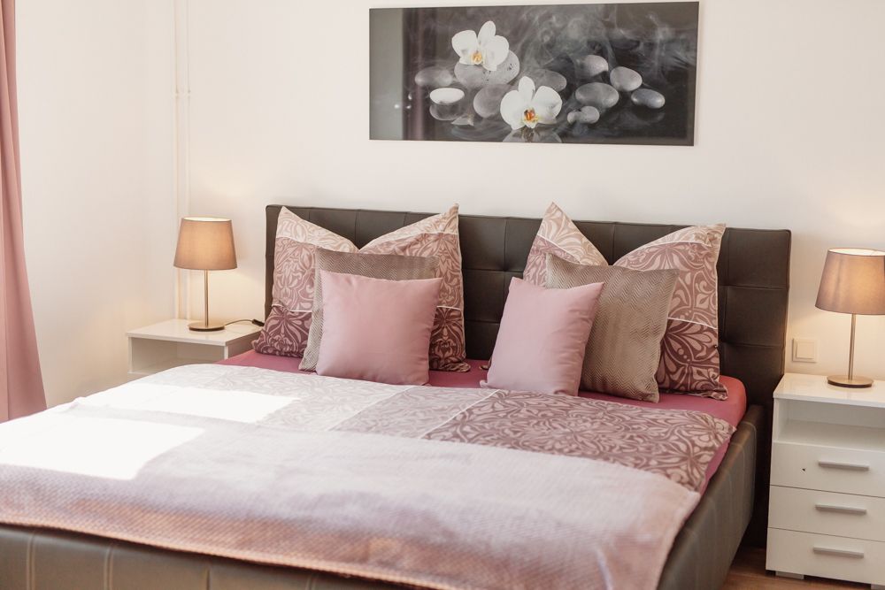 Gemütliches Schlafzimmer mit Doppelbett, rosa Bettwäsche und zwei Nachttischen mit Lampen.