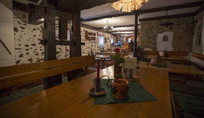 Rustikales Restaurant mit Holztischen und Steinwänden.