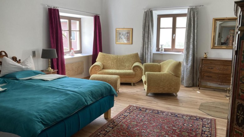 Cozy bedroom with blue bed, yellow armchairs, carpet and wooden furniture.