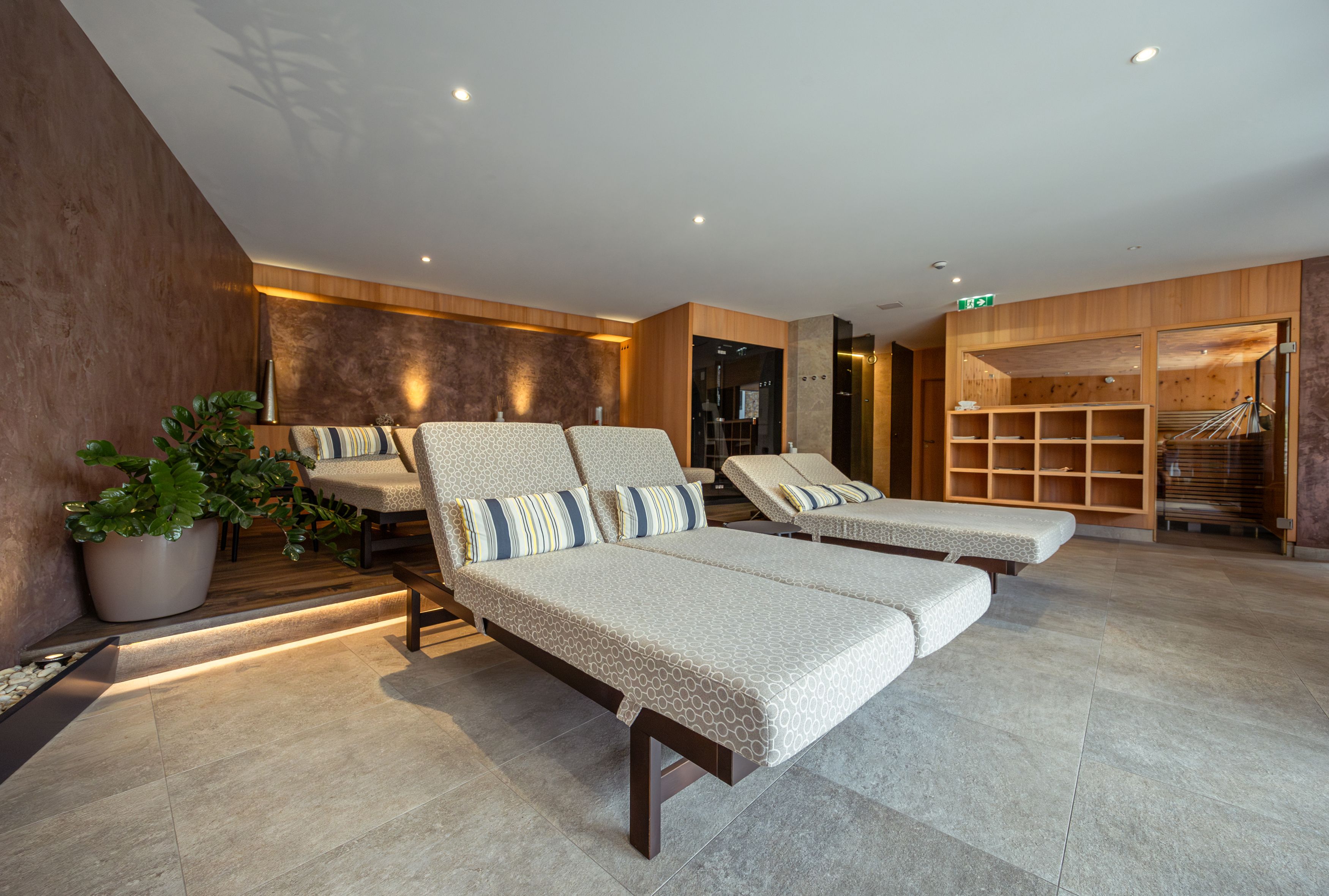 Innenansicht eines modernen Wellnessbereichs mit Liegen und Pflanzen.