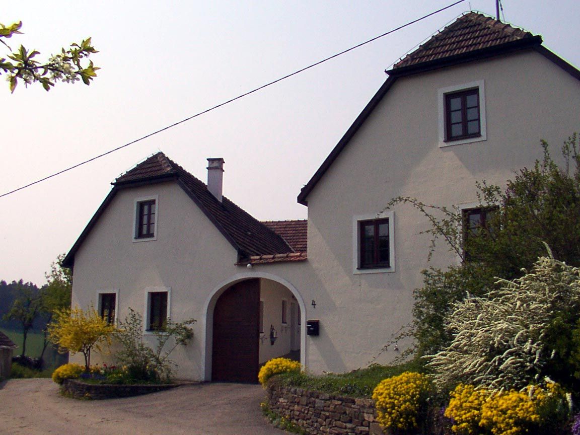 Ein weißes Landhaus mit braunem Dach und Garten.