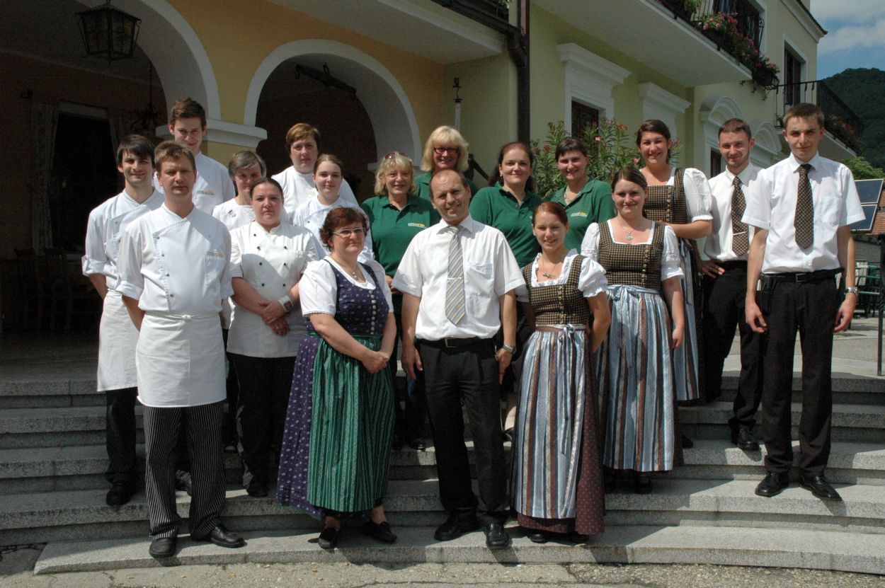 Eine Gruppe von Menschen in Arbeitskleidung steht vor einem Gebäude mit Bögen.