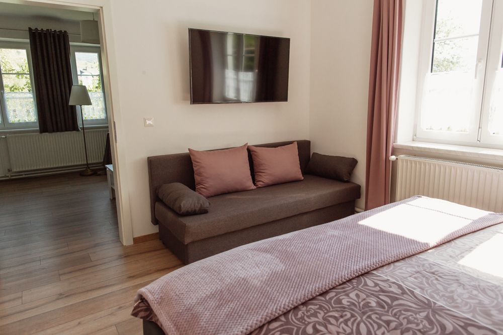 Modernes Wohnzimmer mit Sofa, Flachbildfernseher und Fenster mit rosa Vorhängen.