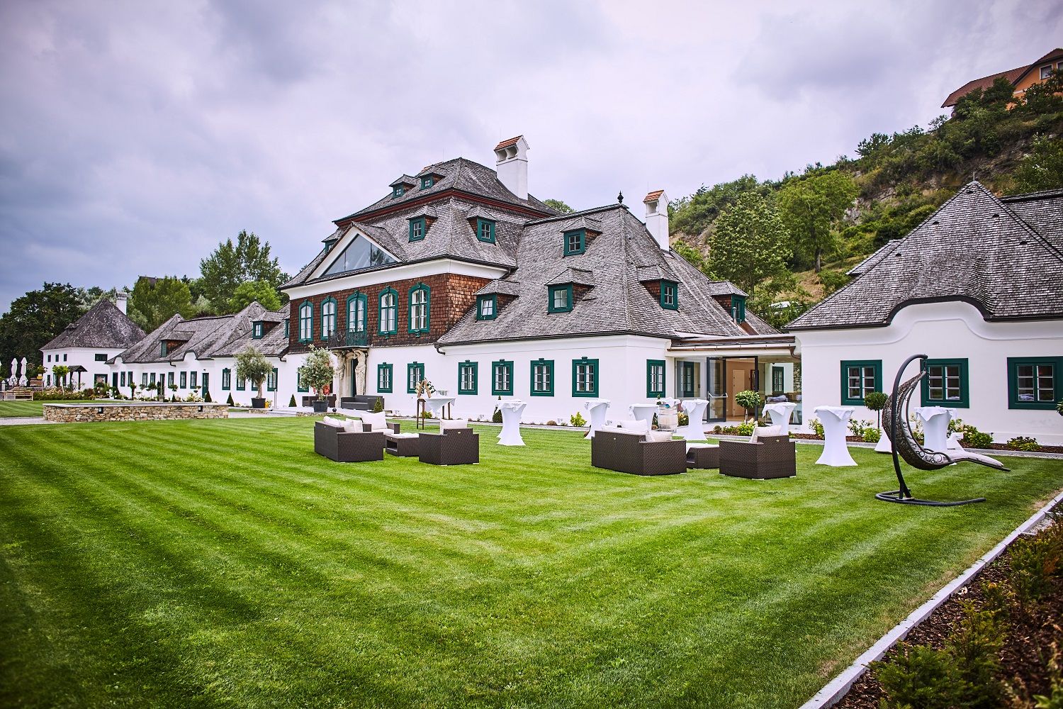 Schloss Luberegg mit gepflegtem Rasen und Gartenmöbeln im Vordergrund.