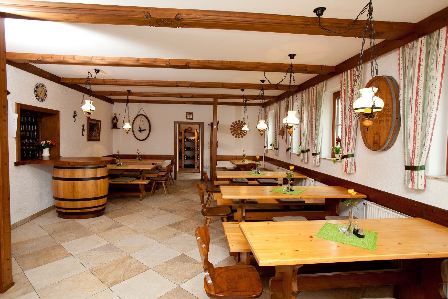 Innenansicht eines Heurigenlokals mit Holztischen, Stühlen und rustikaler Dekoration.