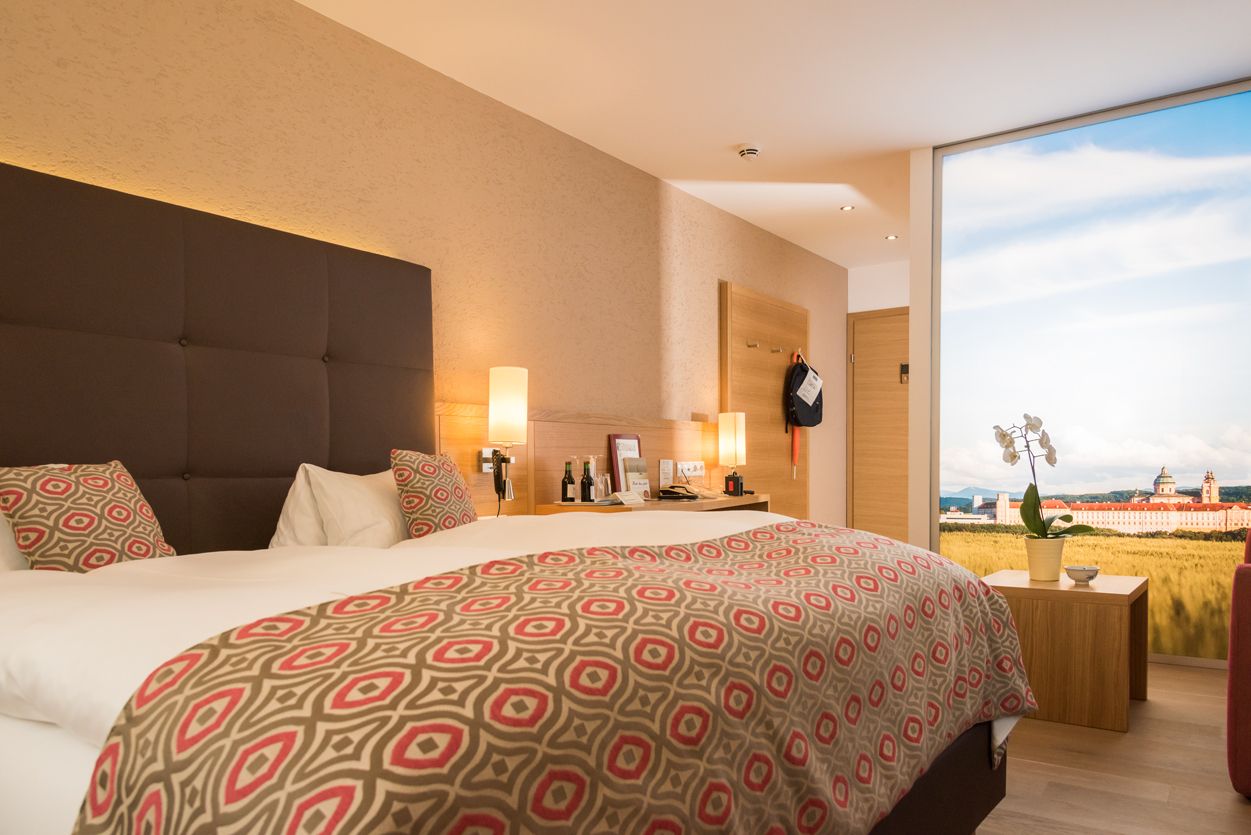 Modernes Hotelzimmer mit Doppelbett, stilvollen Lampen und großem Fenster mit Landschaftsansicht.