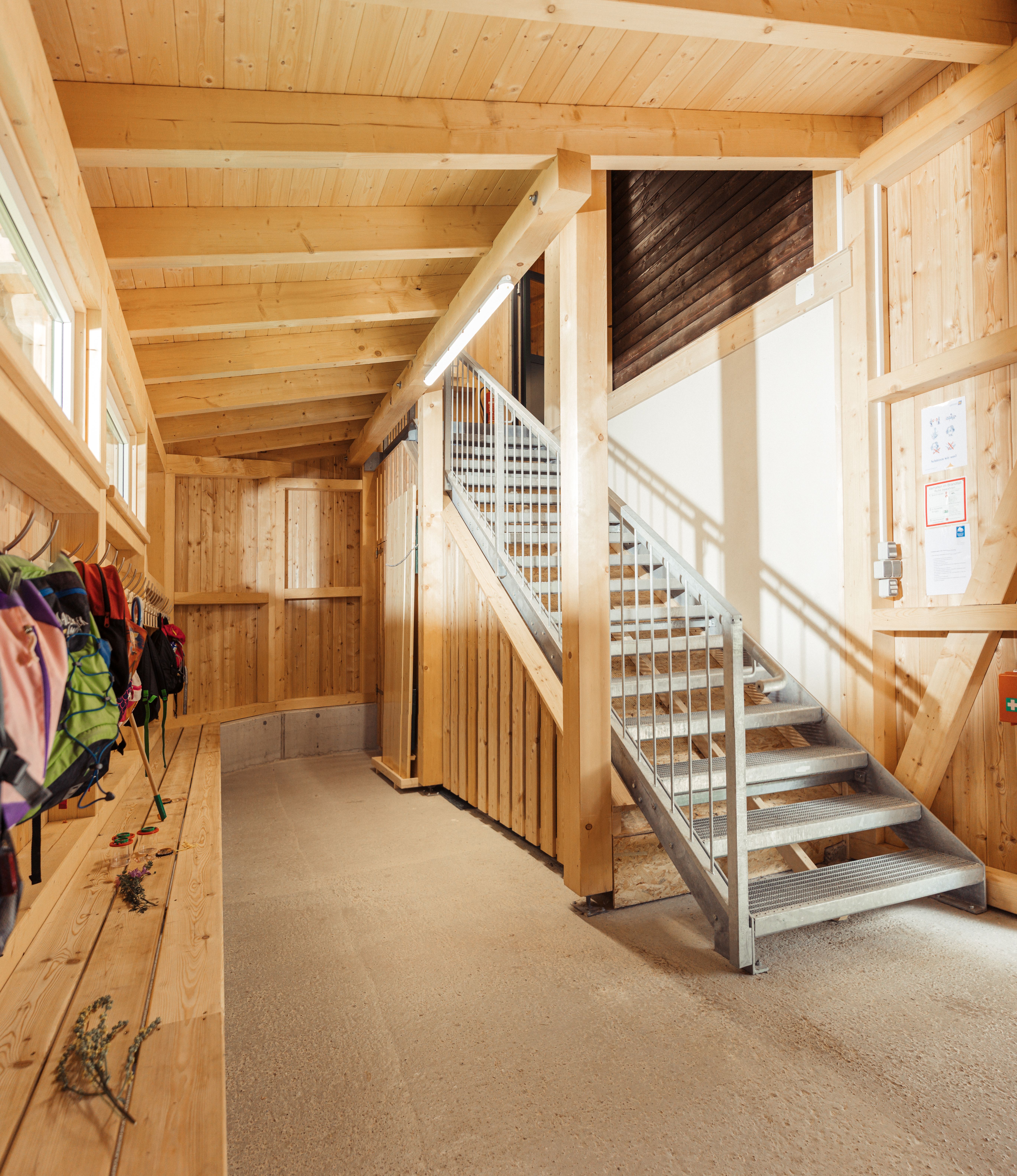 Eine Aluminiumtreppe in der Naturwerkstatt, neben ihr ist eine lange Garderobe mit Bank.