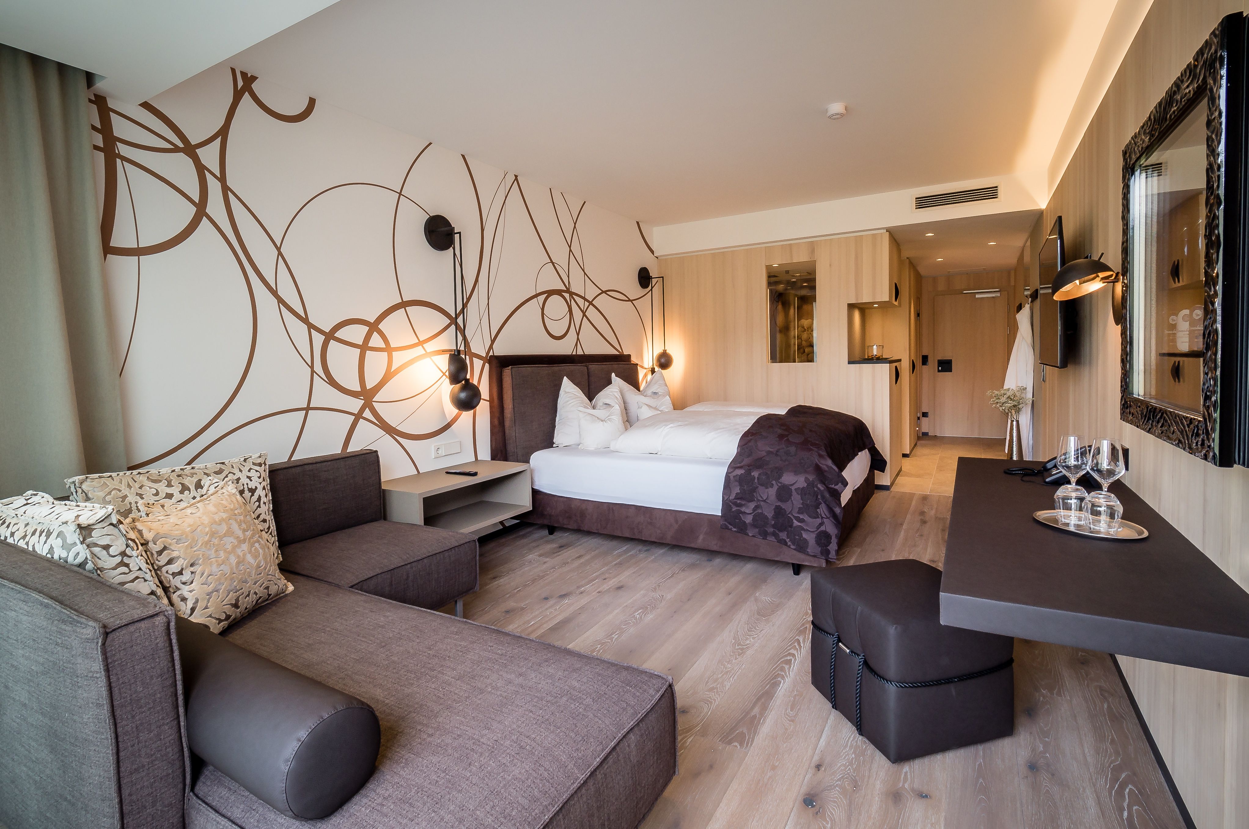 Modern eingerichtetes Hotelzimmer mit Doppelbett, Sofa und Schreibtisch.