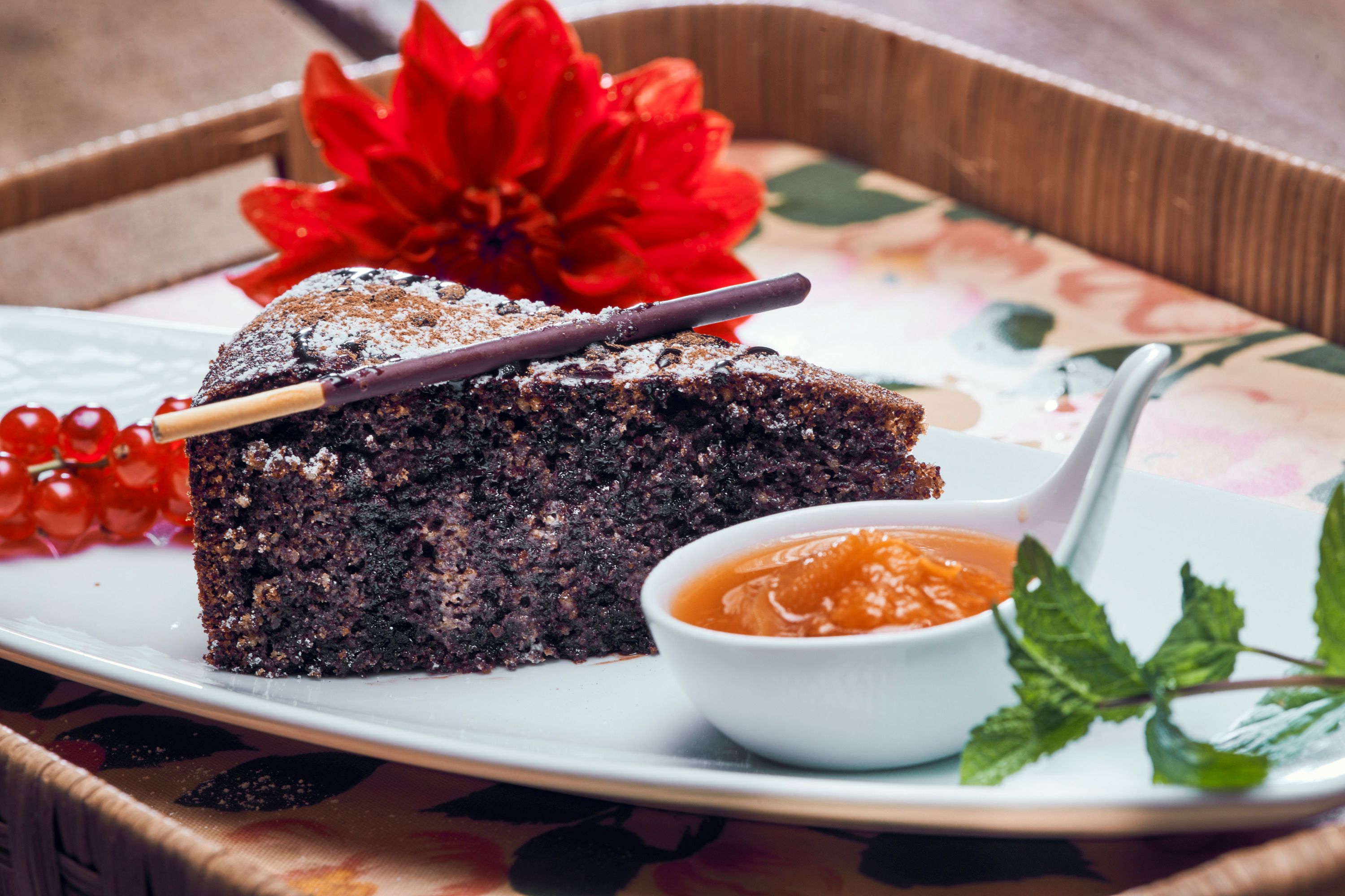 Mohnkuchen mit Puderzucker, Beeren und Aprikosenmarmelade auf Teller.