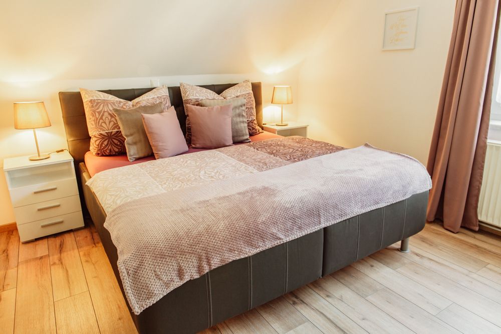 Gemütliches Schlafzimmer mit Doppelbett, Nachttischen und Lampen.