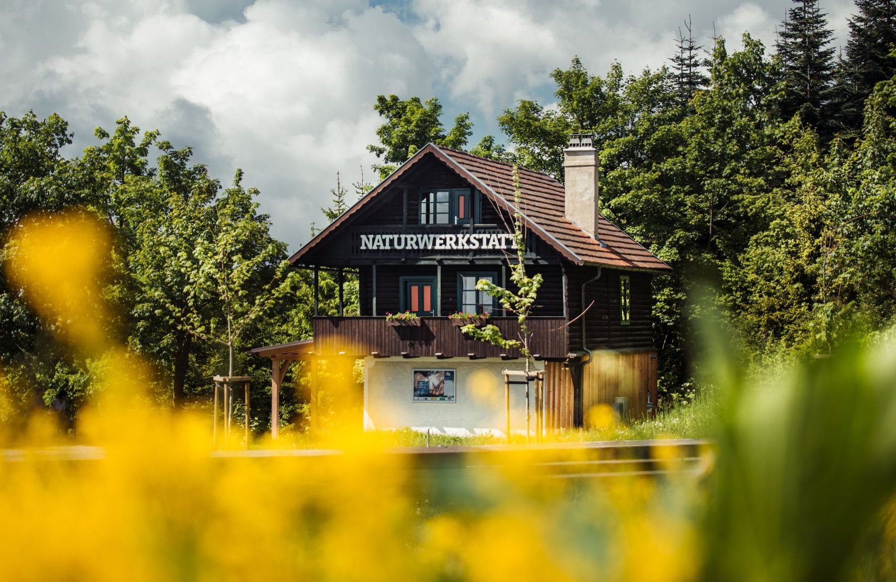 Ein Idyllisches Haus mit der Aufschrift Naturwerkstatt, auf einer kleinen Wiese