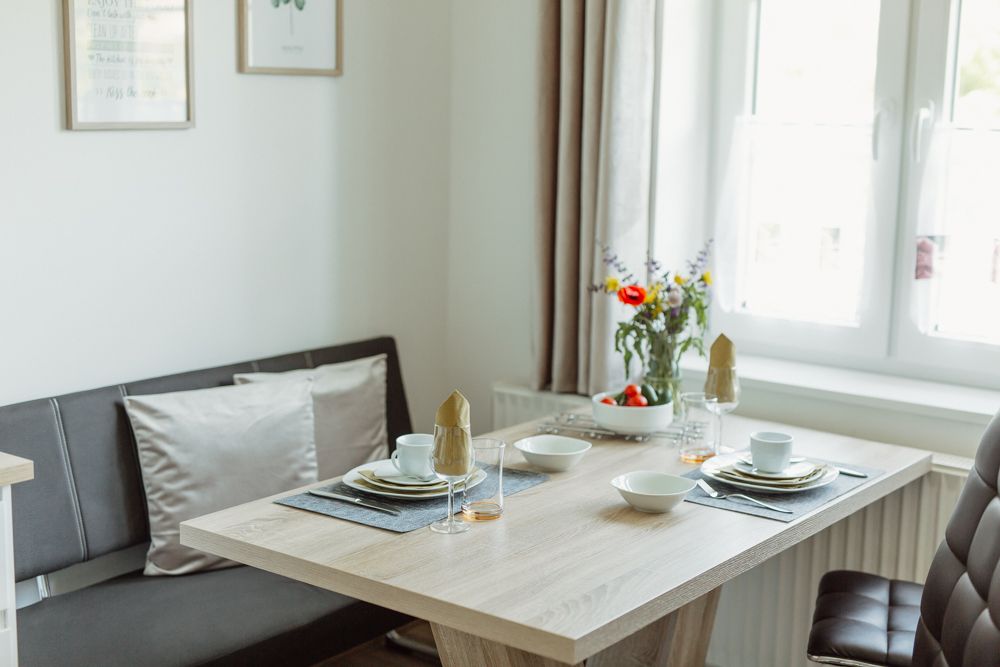 Essbereich in einem modernen Appartement mit gedecktem Tisch und Blumen.