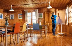 Ein Großer Seminarraum mit Whiteboard, Tisch und Sesseln.