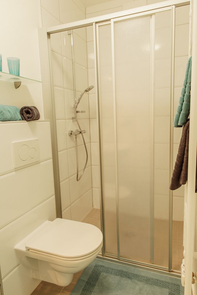 Kleines Badezimmer mit Dusche, Toilette und Handtüchern.