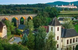 Eine Eisenbahnbrücke und ein kleines schloss, im Hintergrund das Stift Melk