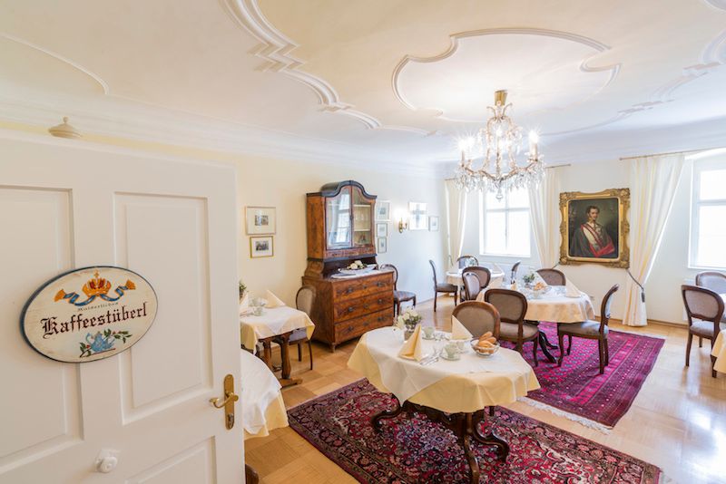 Elegantes Café im Barockstil mit Kronleuchter und antiken Möbeln.