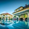 Die Gartenvilla mit großem Pool im Vordergrund, umgeben von Pflanzen und Liegestühlen.