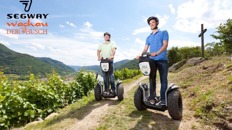 Zwei M&auml;nner fahren auf Segways durch eine Weinberglandschaft in der Wachau.