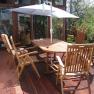 Wooden terrace with table, chairs and parasol.