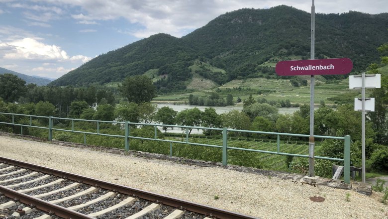 Schwallenbach station with tracks, green hills in the background.