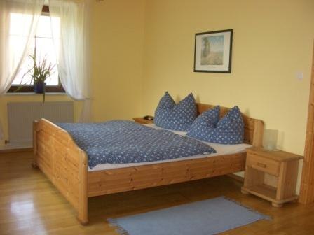 Schlafzimmer mit Holzbett, blauer Bettwäsche und Nachttisch.