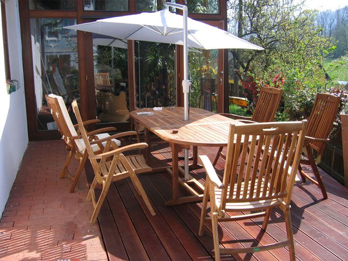 Holzterrasse mit Tisch, Stühlen und Sonnenschirm.