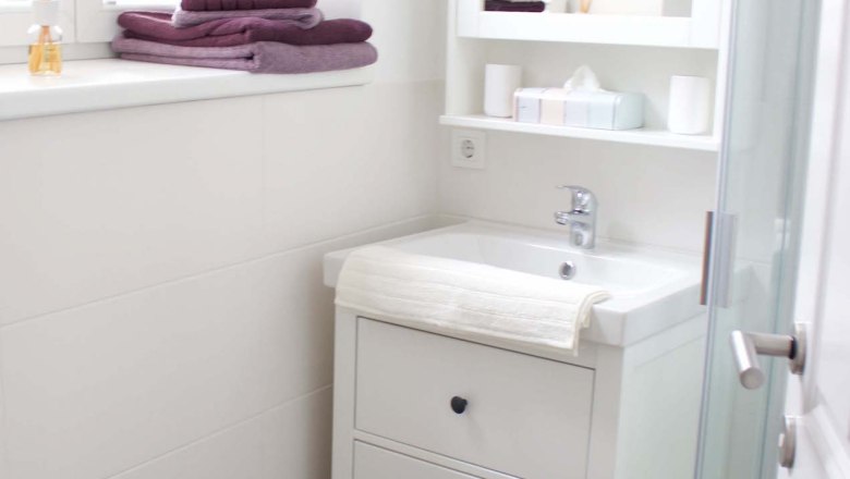 Modernes Badezimmer mit weißem Waschbecken, Spiegel, Handtüchern und Dusche.