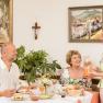Three people at breakfast, a woman serves orange juice.