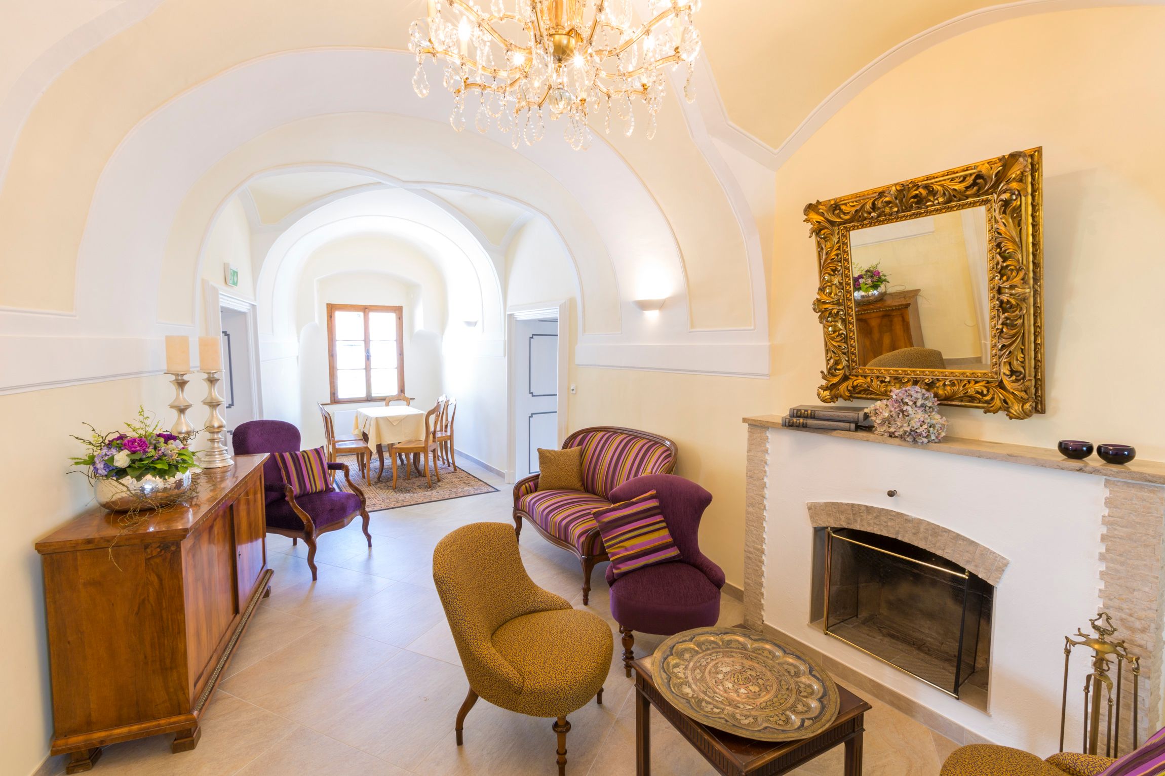 Eleganter Raum mit Kamin, antiken Möbeln und Kronleuchter.
