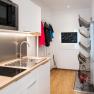 Modern kitchen with sink, microwave, jackets on hooks and ski boot dryer.