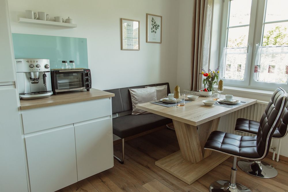 Moderne Küche mit Esstisch, Stühlen und Kaffeemaschine.