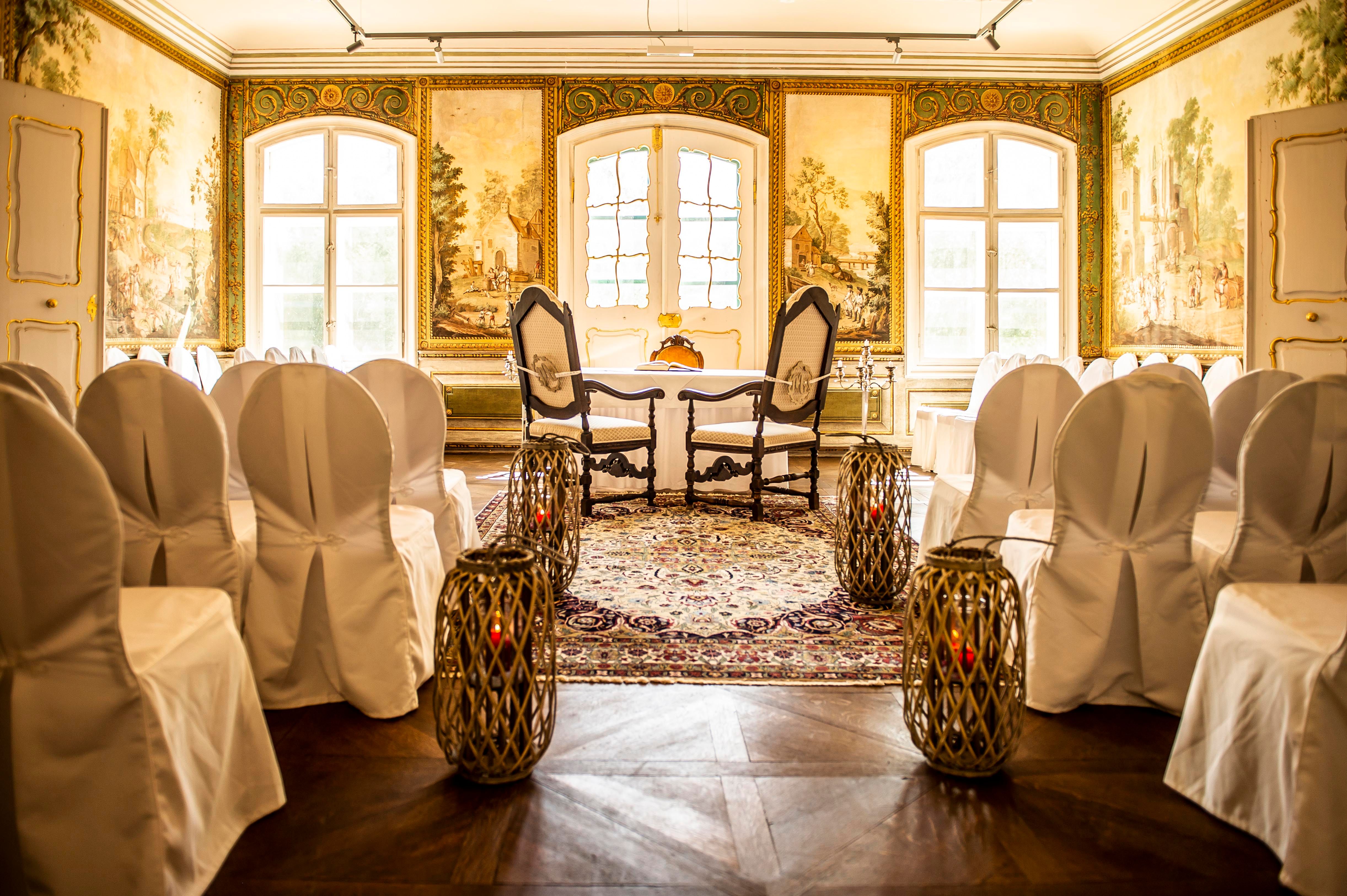 State Hall in Schloss Luberegg with decorated chairs, carpet and wall paintings.