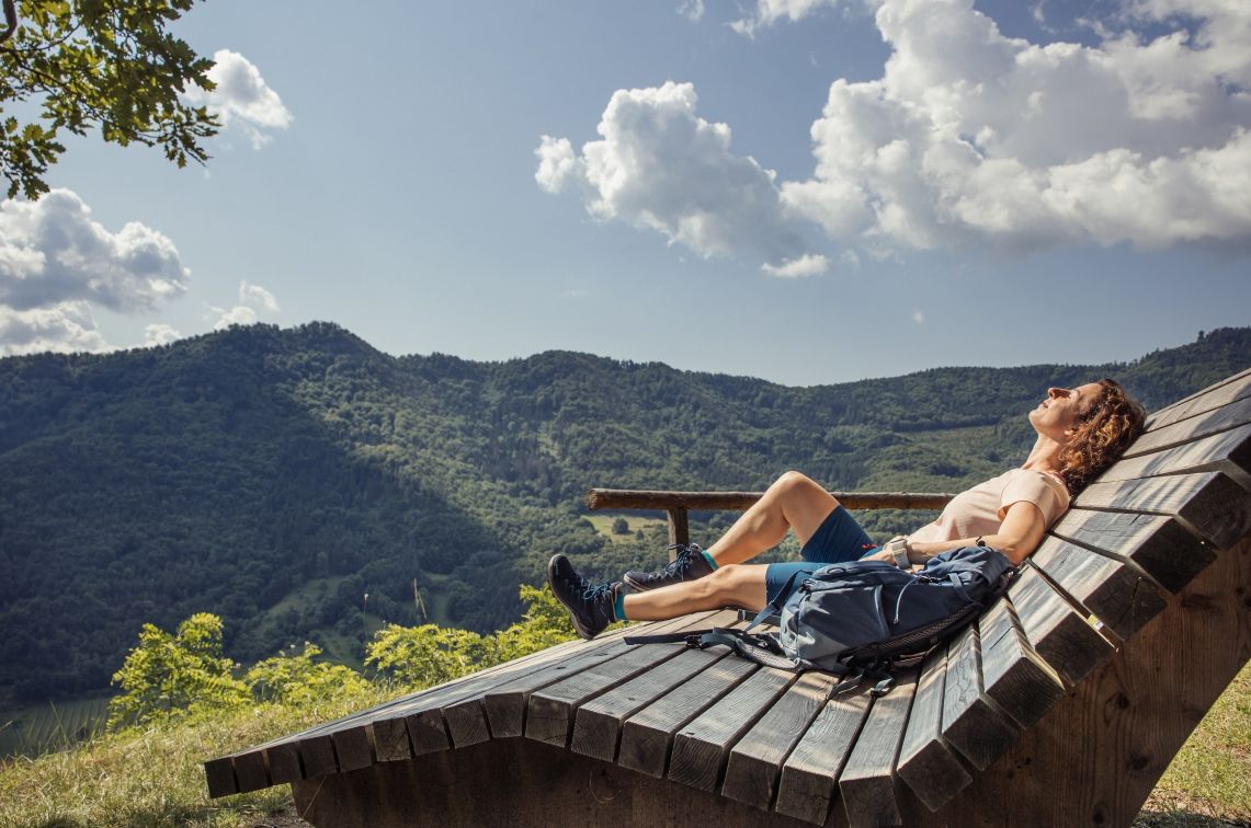 Eine Frau sonnt sich auf einer großen hölzernen Sonnenliege. 