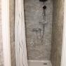 Modern shower with gray tiles and shower curtain.