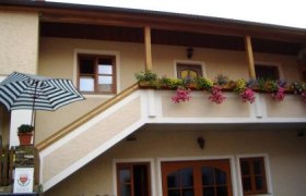 Zweistöckiges Gebäude mit Balkon und Blumen.