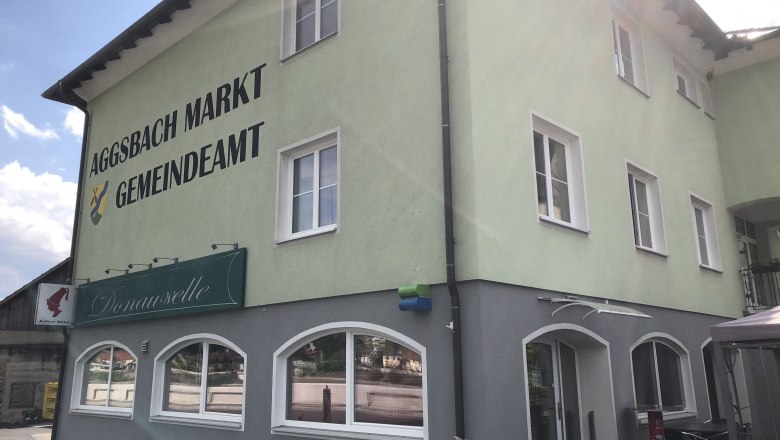 Grünes Gebäude mit Aufschrift 'Aggsbach Markt Gemeindeamt' und Café Donauwelle.