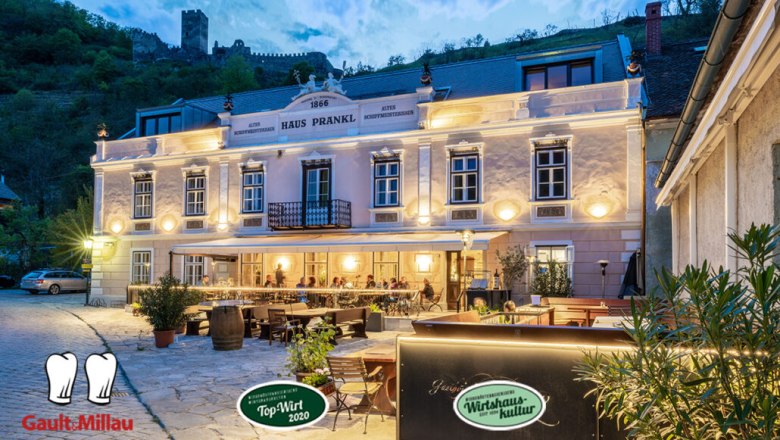 Evening shot of the Gasthof Prankl with illuminated façade and guests on the terrace.