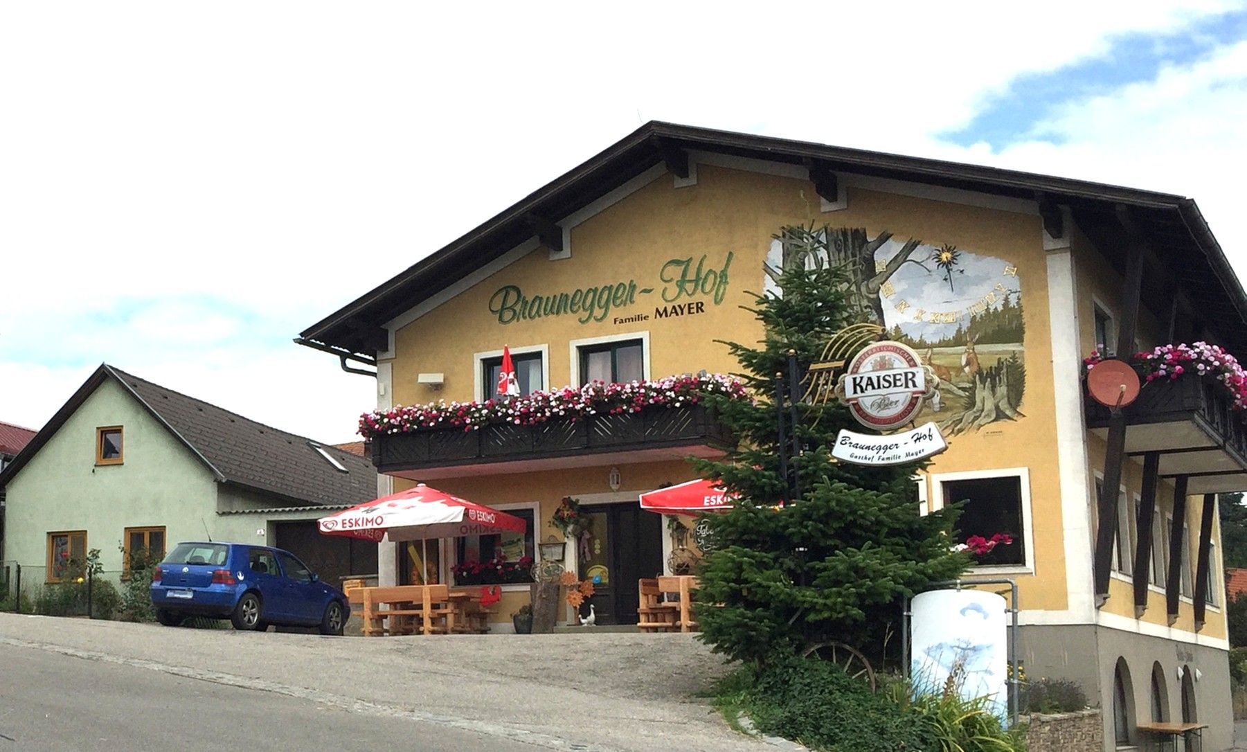 Gasthof Braunegger-Hof mit Balkonblumen und Sonnenschirmen.