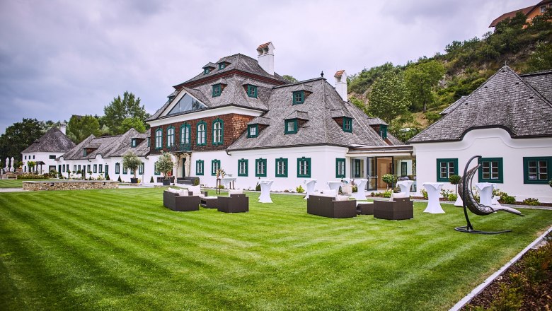 Schloss Luberegg with manicured lawn and garden furniture in the foreground.