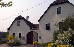 A white country house with a brown roof and garden.