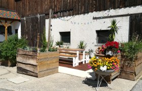 A courtyard with wooden benches, flower boxes and colorful fairy lights.