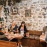 Group of people in a traditional wine tavern with stone walls, food and wine.